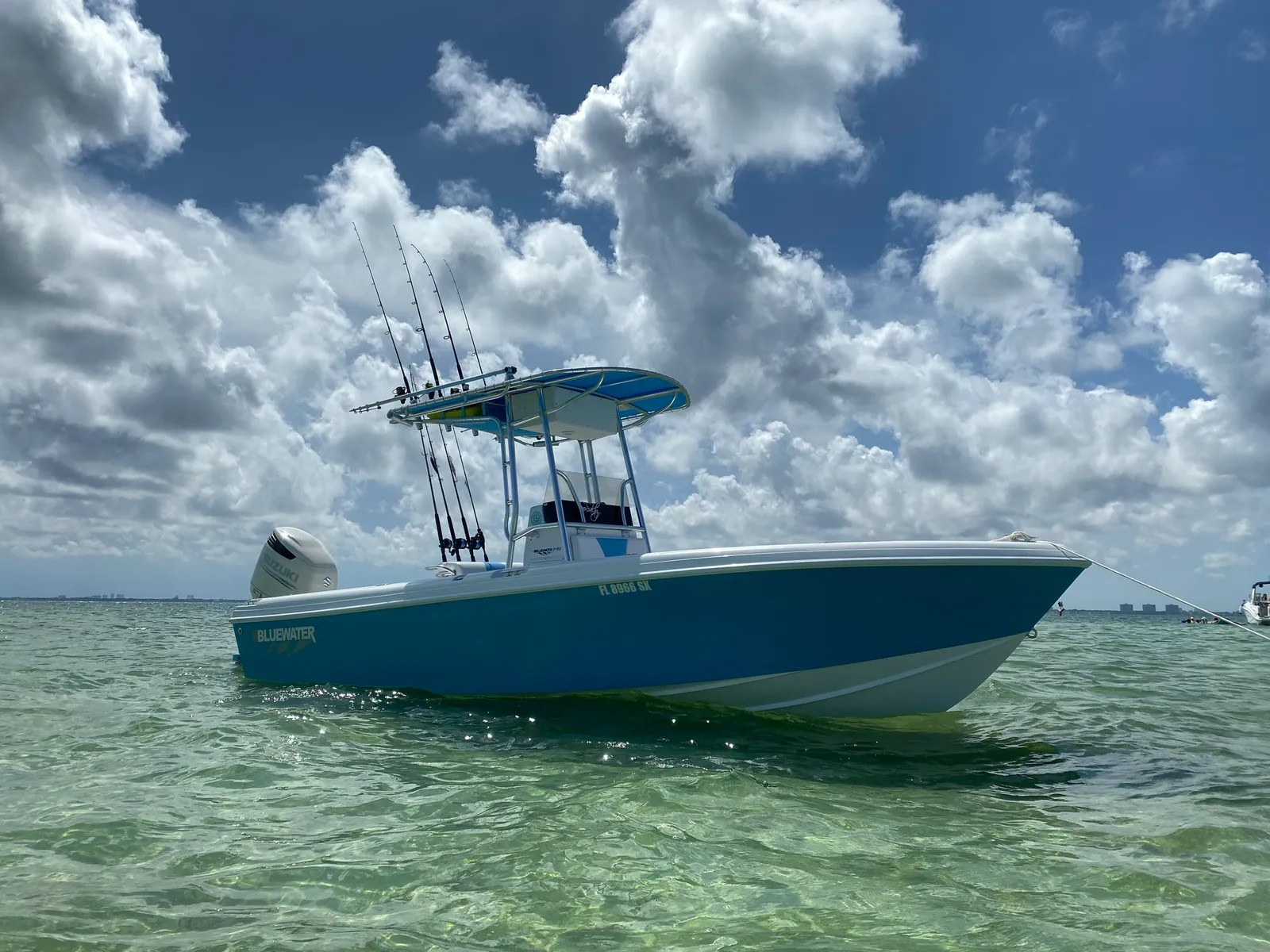 Blue-hulled Bluewater 2150 with a single Suzuki on clear green water